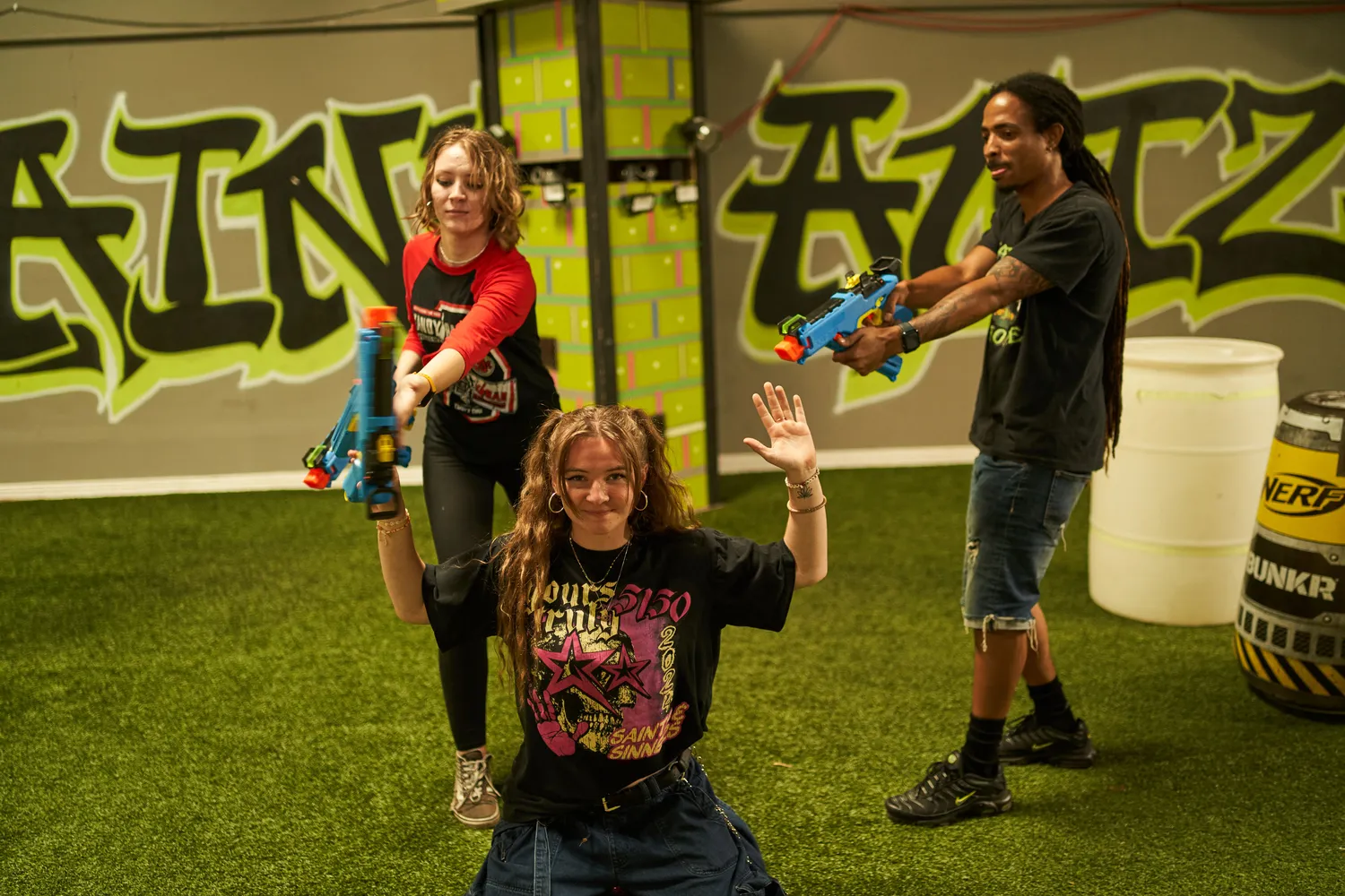 A group of players engaged in a Nerf war, posing energetically with their blasters aimed, showcasing enthusiasm and camaraderie during the event, highlighting the dynamic energy of the competition.