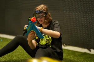 A child wearing protective goggles safely enjoys a Nerf battle, highlighting the importance of eye protection. This demonstrates effective Nerf war safety tips to keep everyone protected. - Brainy Actz Escape Rooms A child wearing protective goggles safely enjoys a Nerf battle, highlighting the importance of eye protection. This demonstrates effective Nerf war safety tips to keep everyone protected.