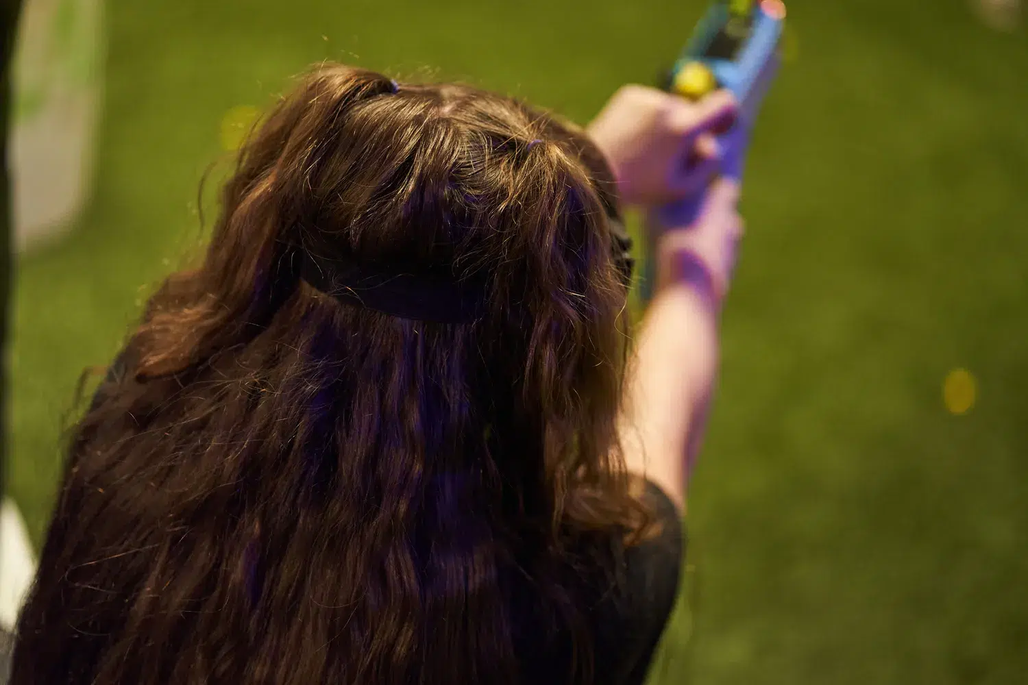 A player with long wavy hair aiming a Nerf gun in a competitive game.