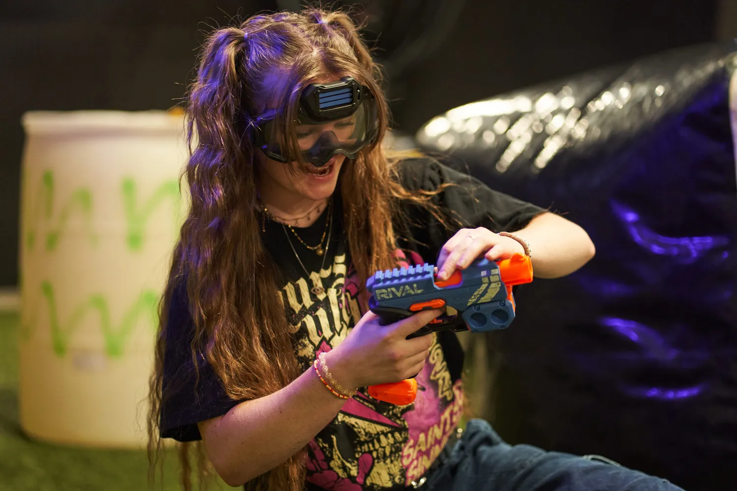 Excited player in protective goggles holding a Nerf blaster, highlighting engagement in a competitive arena.