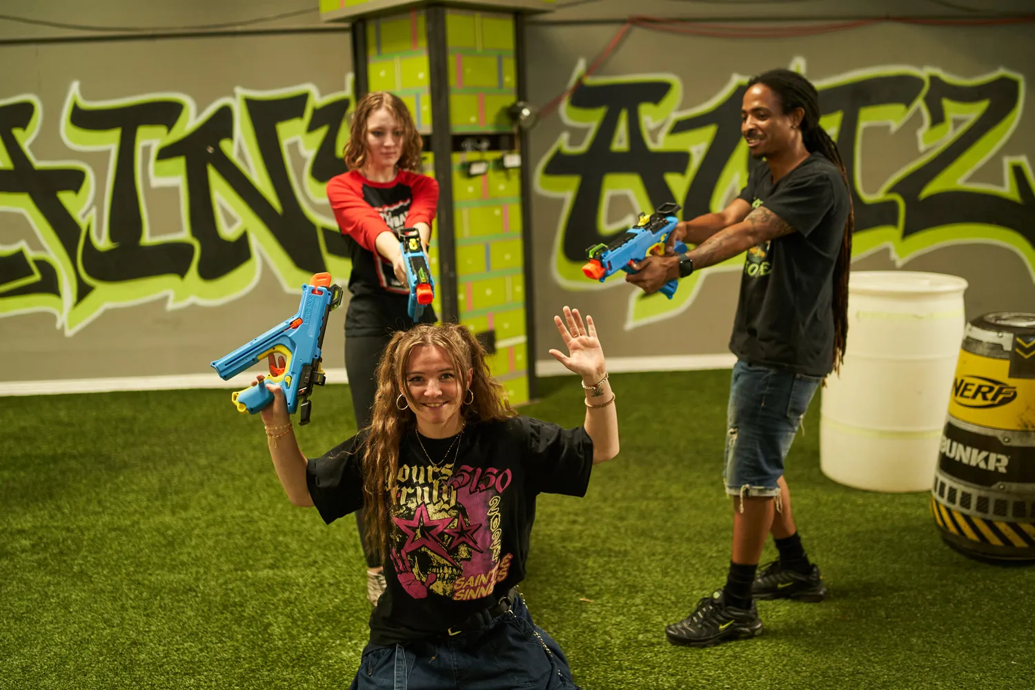 A group of friends playing an exciting Nerf gun battle in an indoor arena.