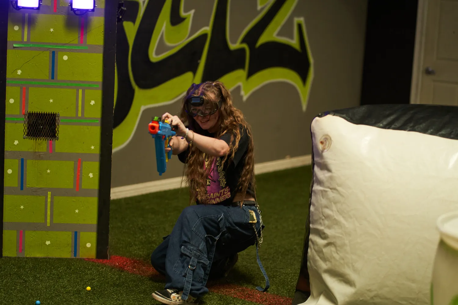 A participant wearing safety goggles and aiming a Nerf blaster in an indoor venue, highlighting the importance of safety during Nerf event activities.