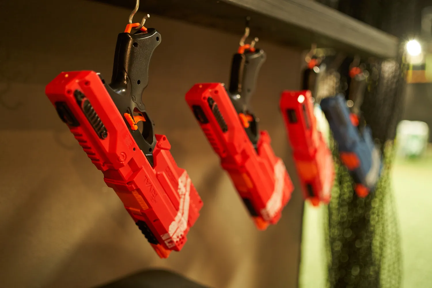 A row of red Nerf blasters hanging neatly in a Nerf arena, emphasizing the importance of proper equipment organization and storage in a Nerf arena. A common mistake to avoid when setting up a Nerf arena is not ensuring that gear and weapons are well-maintained and readily accessible for participants.