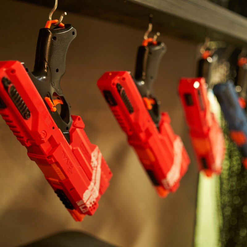 A selection of brightly colored Nerf blasters hanging neatly on a rack, showcasing the variety of models available for purchase.