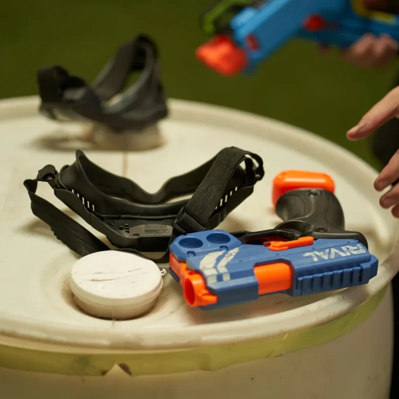 Colorful Nerf blaster and protective gear placed on a table.