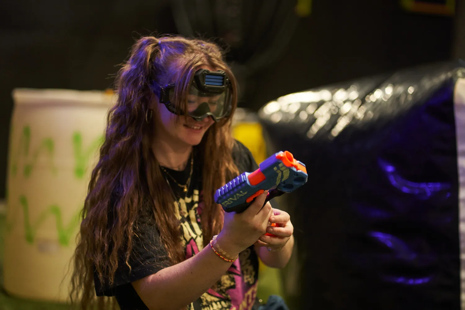 A smiling player wearing safety goggles and holding a Nerf gun during a game.
