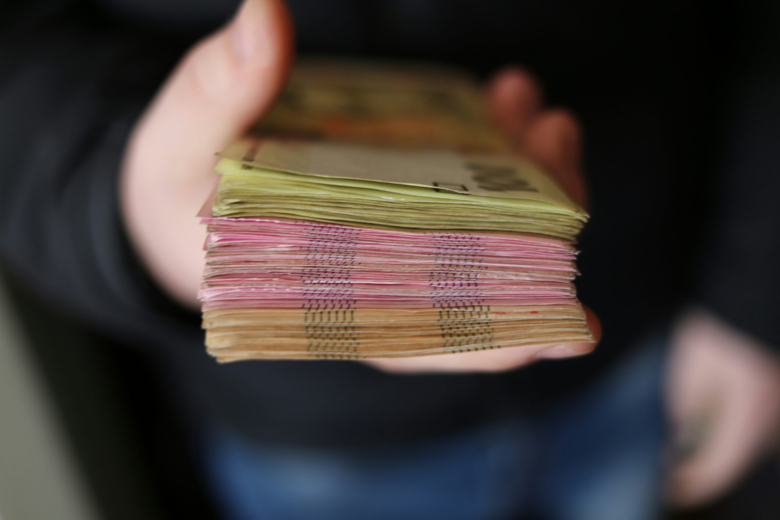 Hand holding a stack of currency notes, symbolizing budget considerations when choosing the best Nerf gun.