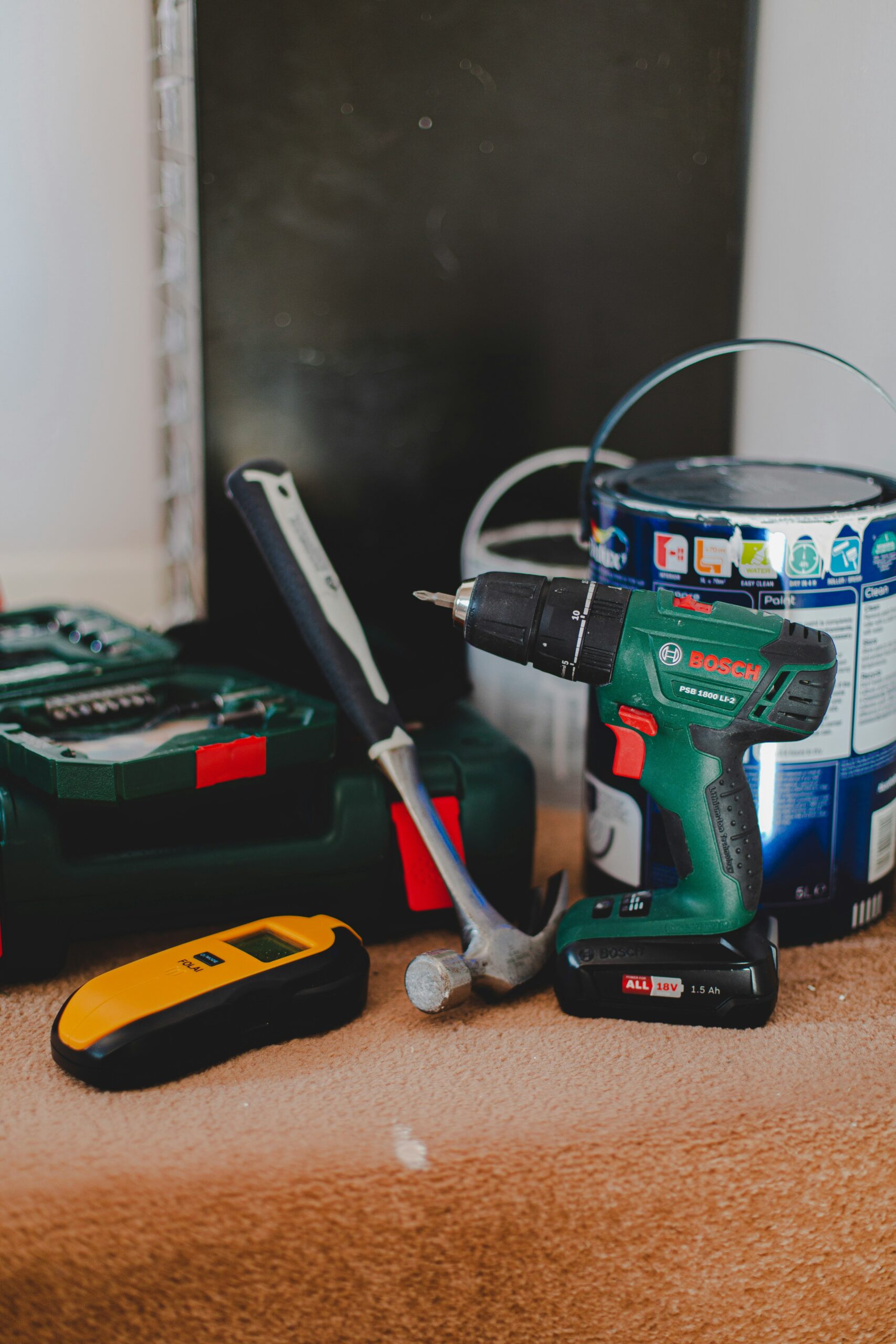 A set of tools including a power drill, hammer, and paint can on a workbench.