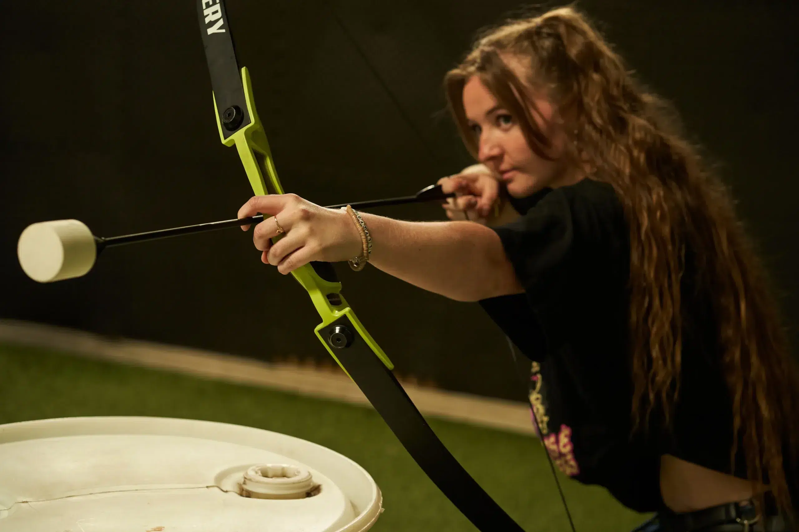 A player aims a foam-tipped arrow using a standard bow, demonstrating cost-effective gear options for Archery Tag.