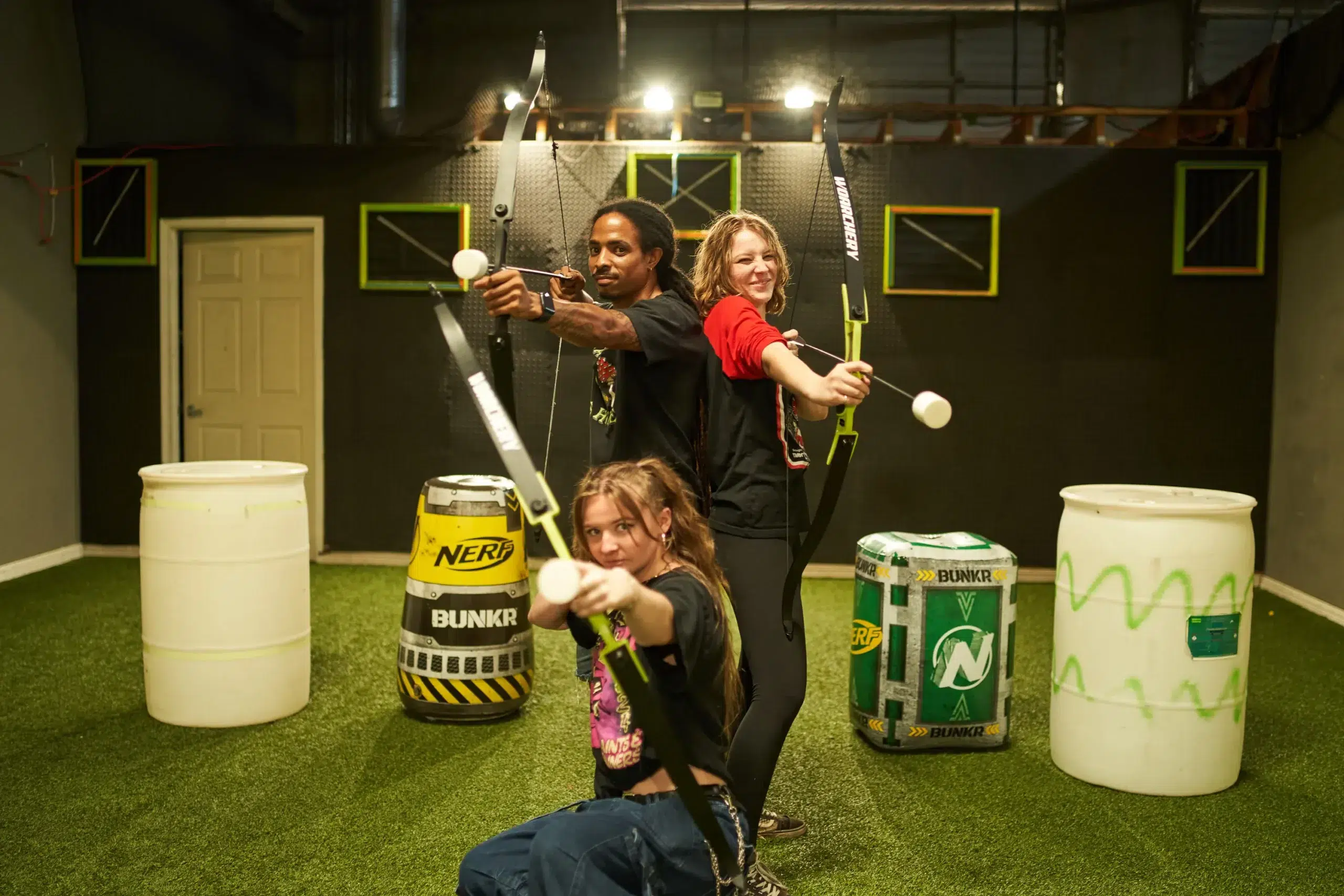Three players posing with foam-tipped arrows and custom archery bows, highlighting personalized gear setups often reviewed in Arrow Tag communities. - Brainy Actz Escape Rooms Three players posing with foam-tipped arrows and custom archery bows, highlighting personalized gear setups often reviewed in Arrow Tag communities.