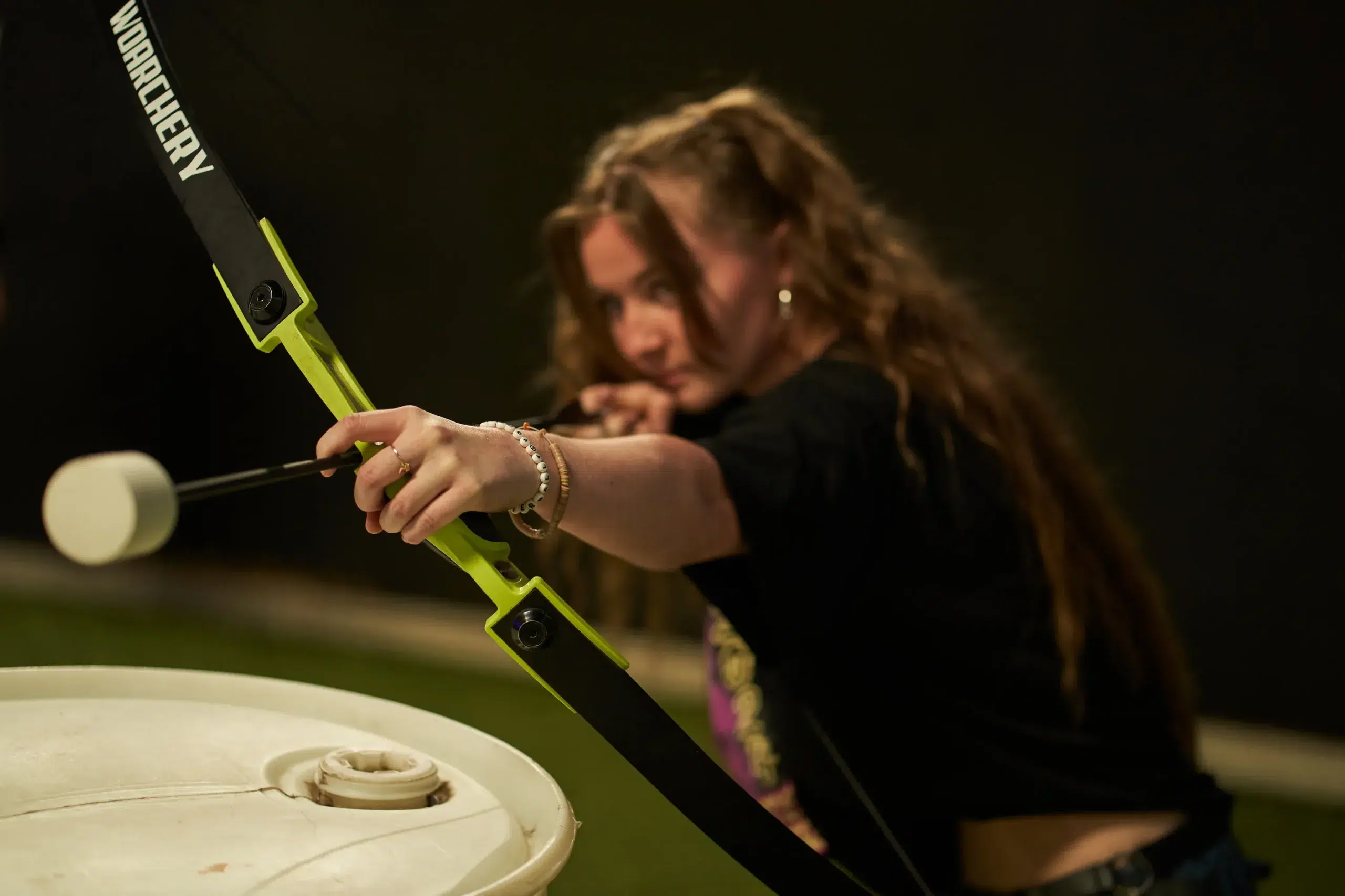 A focused player draws a foam-tipped arrow in an indoor arena, emphasizing the importance of setting clear safety rules before starting an arrow tag game. - Brainy Actz Escape Rooms A focused player draws a foam-tipped arrow in an indoor arena, emphasizing the importance of setting clear safety rules before starting an arrow tag game.
