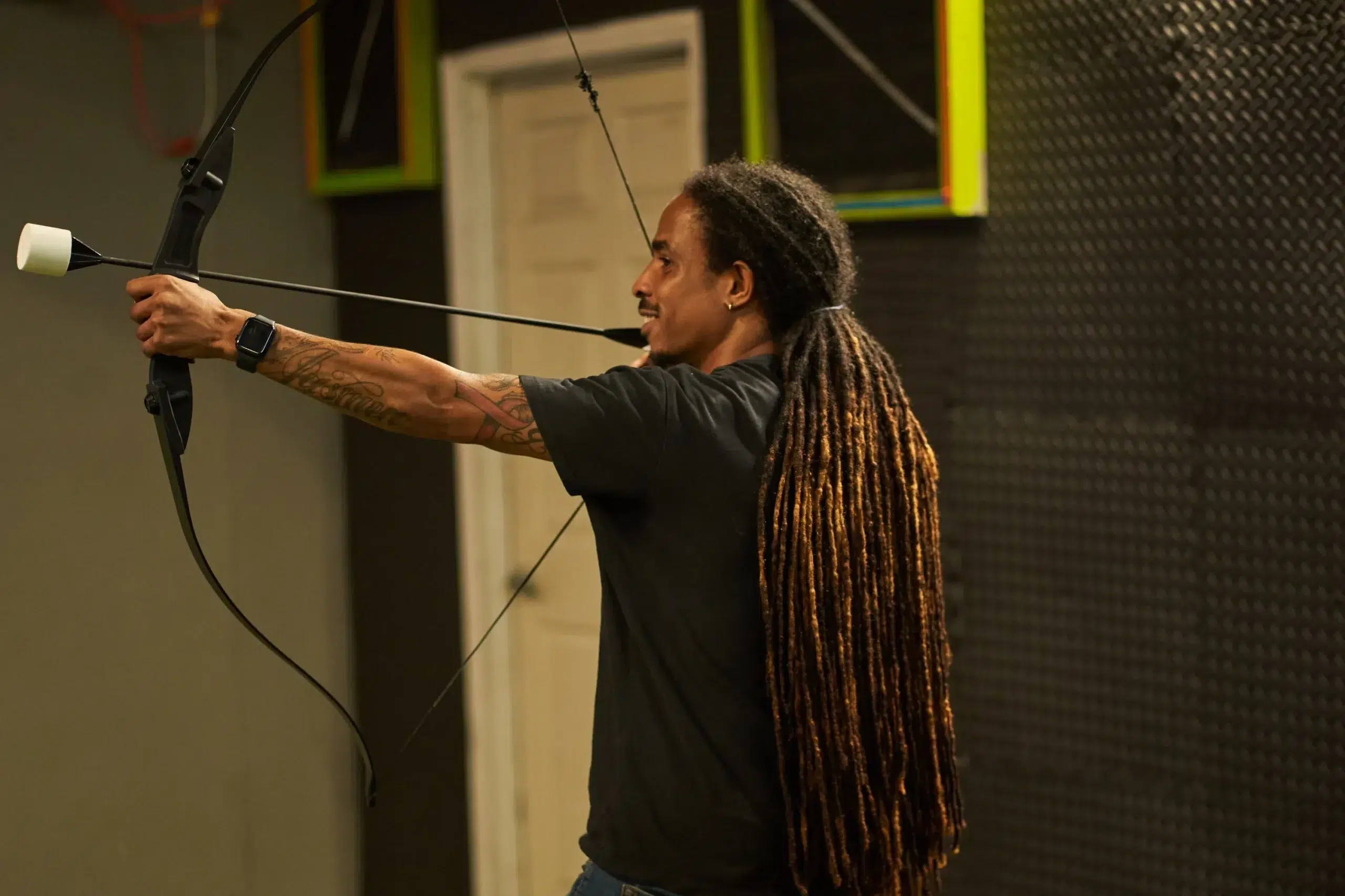 A player aims a foam-tipped arrow using a beginner-friendly recurve bow, perfect for new Archery Arrow Tag participants. - Brainy Actz Escape Rooms A player aims a foam-tipped arrow using a beginner-friendly recurve bow, perfect for new Archery Arrow Tag participants.