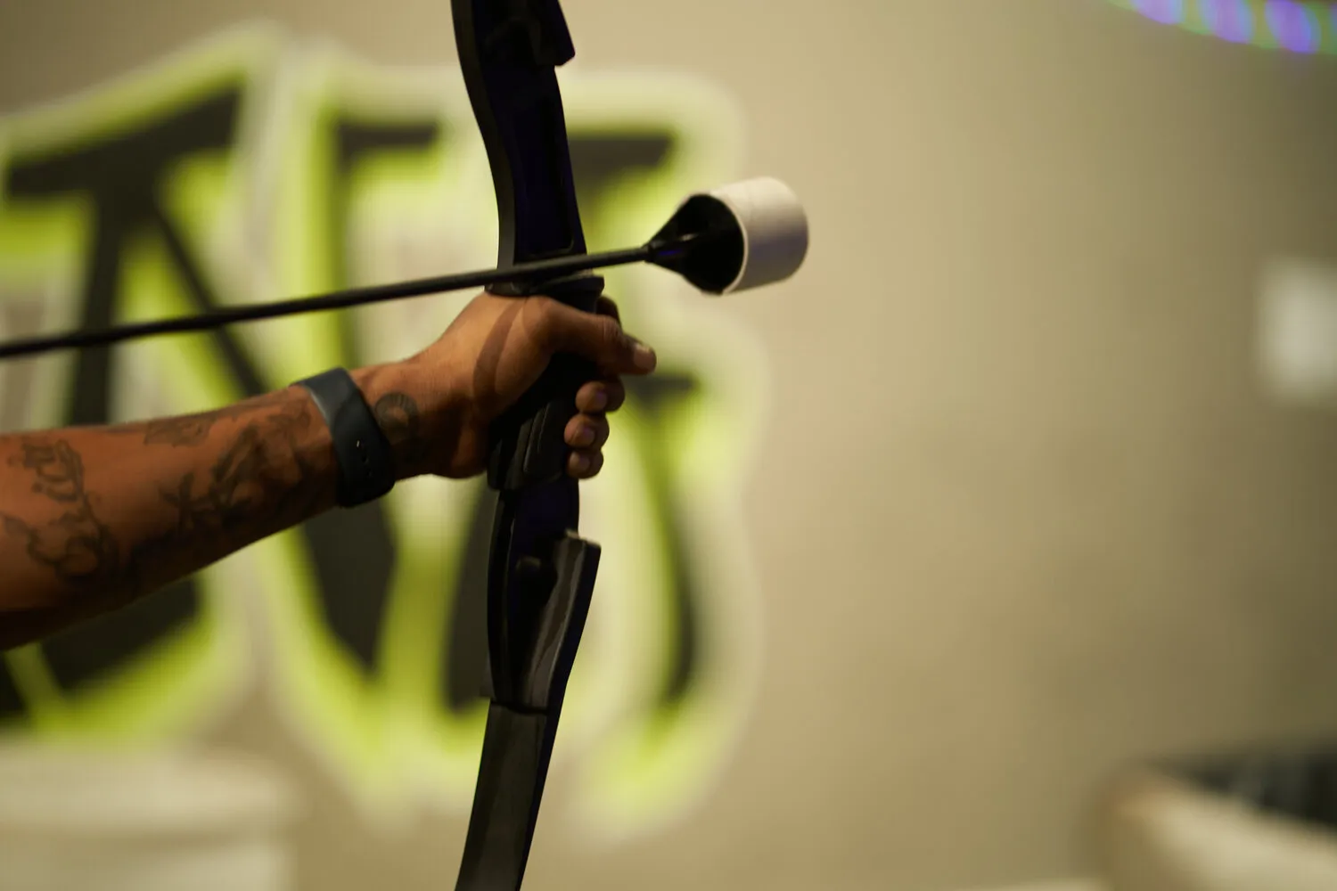 A close-up of a person holding a bow and foam-tipped arrow, highlighting the importance of safe equipment in archery tag. - Brainy Actz Escape Rooms A close-up of a person holding a bow and foam-tipped arrow, highlighting the importance of safe equipment in archery tag.