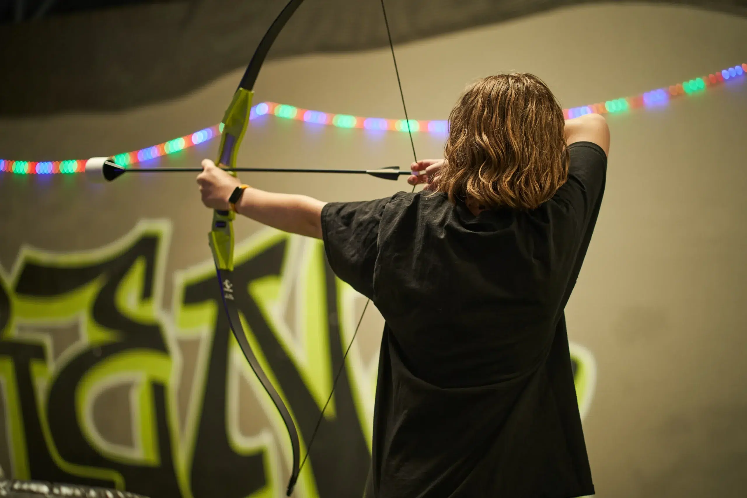 A player aims a foam-tipped arrow using a bow, highlighting how correct gear usage plays a key role in maintaining safety during archery arrow tag. - Brainy Actz Escape Rooms A player aims a foam-tipped arrow using a bow, highlighting how correct gear usage plays a key role in maintaining safety during archery arrow tag.