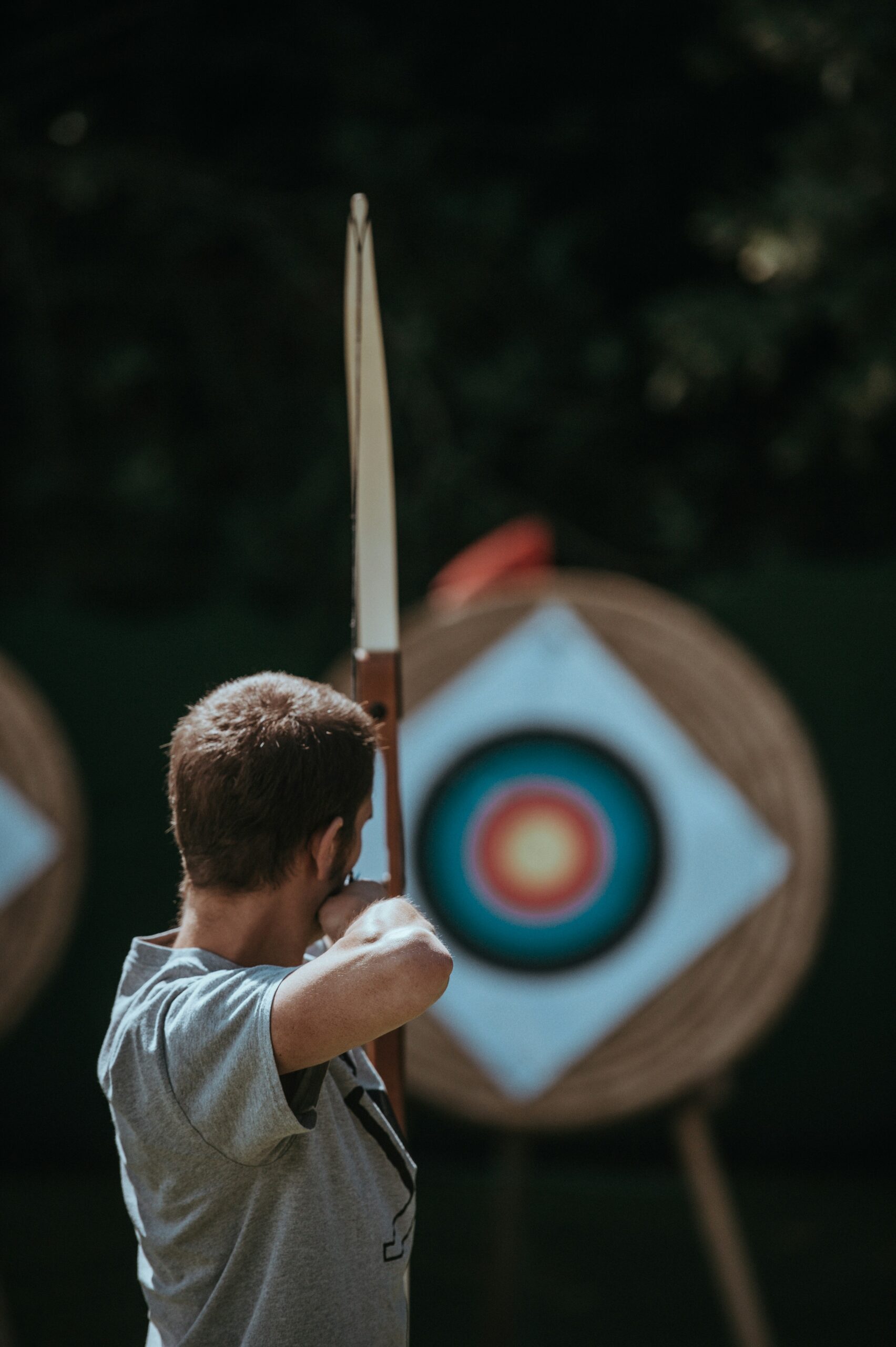 A person aims a bow at a target during practice, underscoring the importance of setting clear safety rules before starting arrow tag. - Brainy Actz Escape Rooms A person aims a bow at a target during practice, underscoring the importance of setting clear safety rules before starting arrow tag.