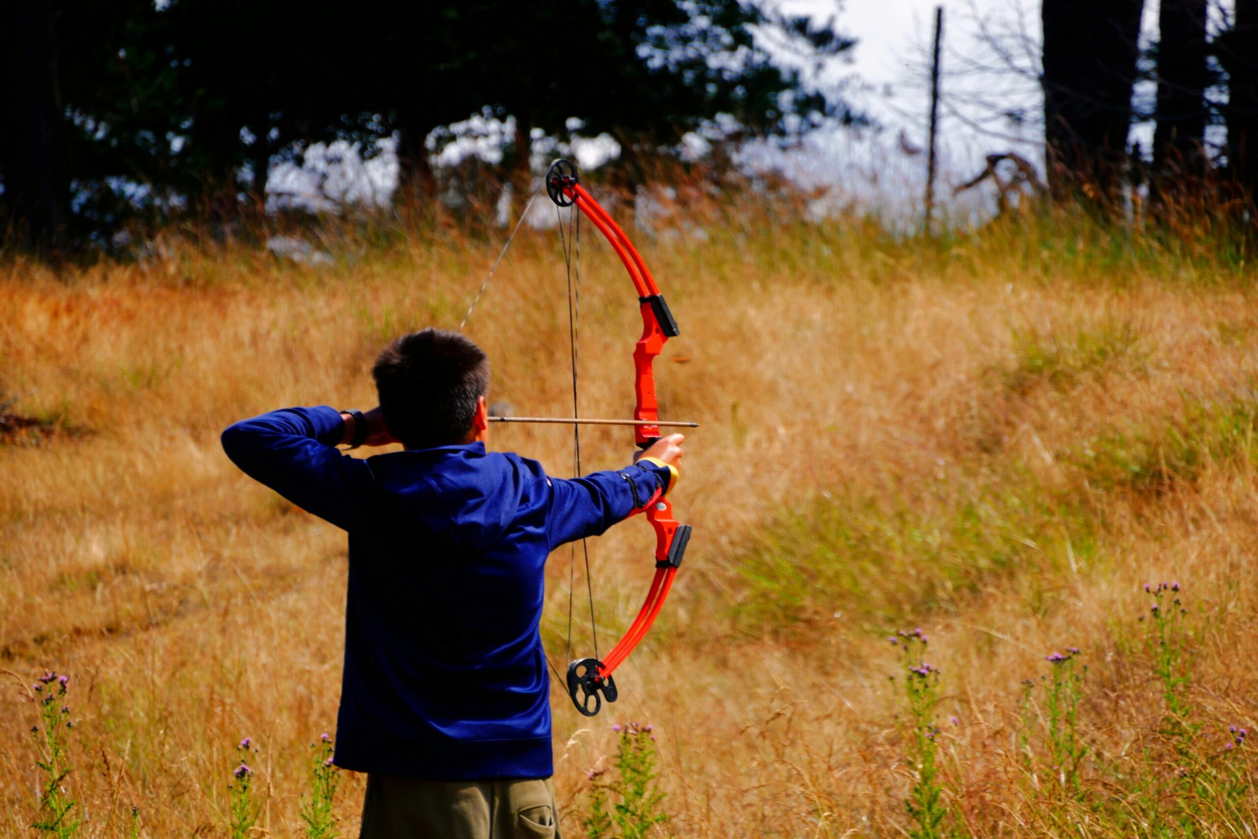 A child draws a bow in an open field, highlighting the importance of active supervision and monitoring during children's arrow tag games. - Brainy Actz Escape Rooms A child draws a bow in an open field, highlighting the importance of active supervision and monitoring during children's arrow tag games.