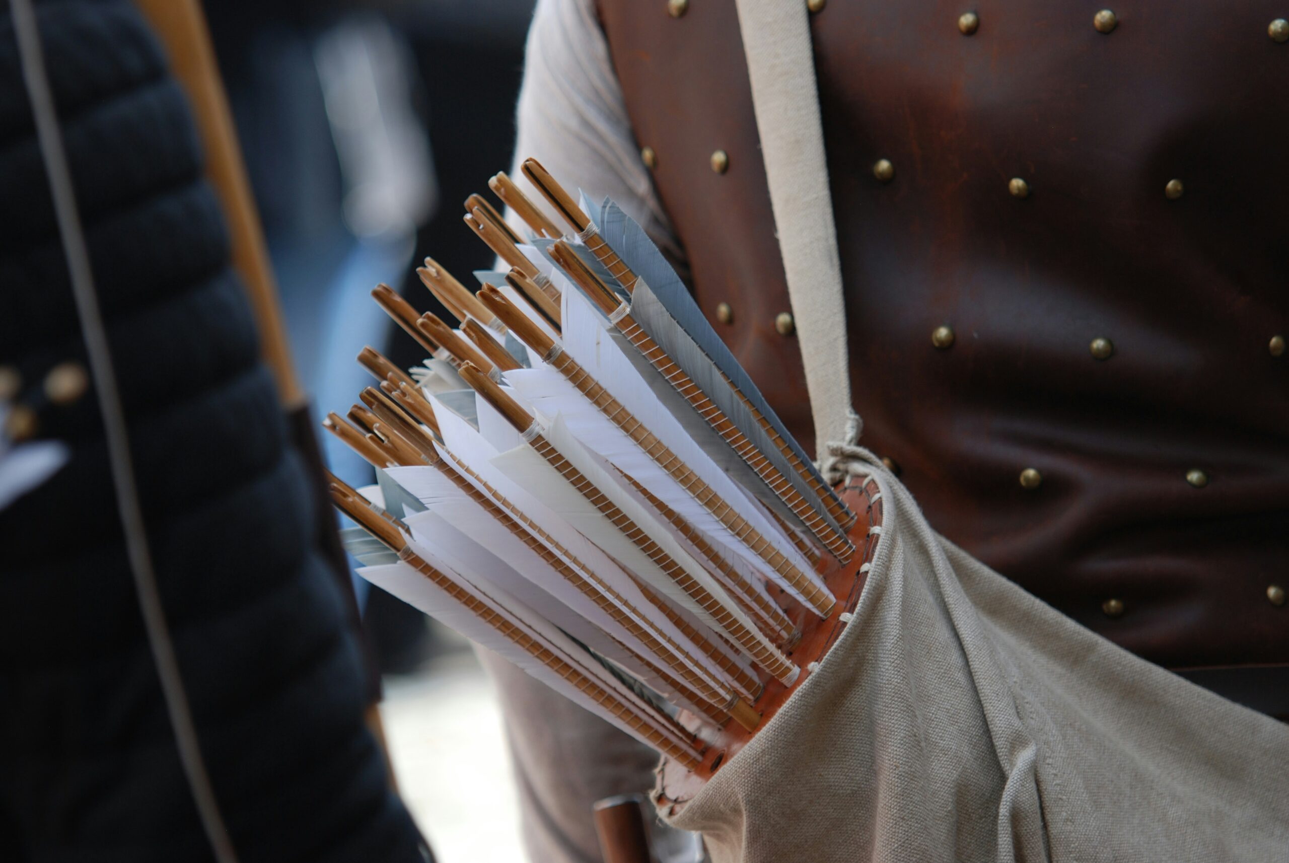 A close-up of arrows in a quiver worn over padded armor, emphasizing the importance of proper gear selection and upkeep in archery tag. - Brainy Actz Escape Rooms A close-up of arrows in a quiver worn over padded armor, emphasizing the importance of proper gear selection and upkeep in archery tag.