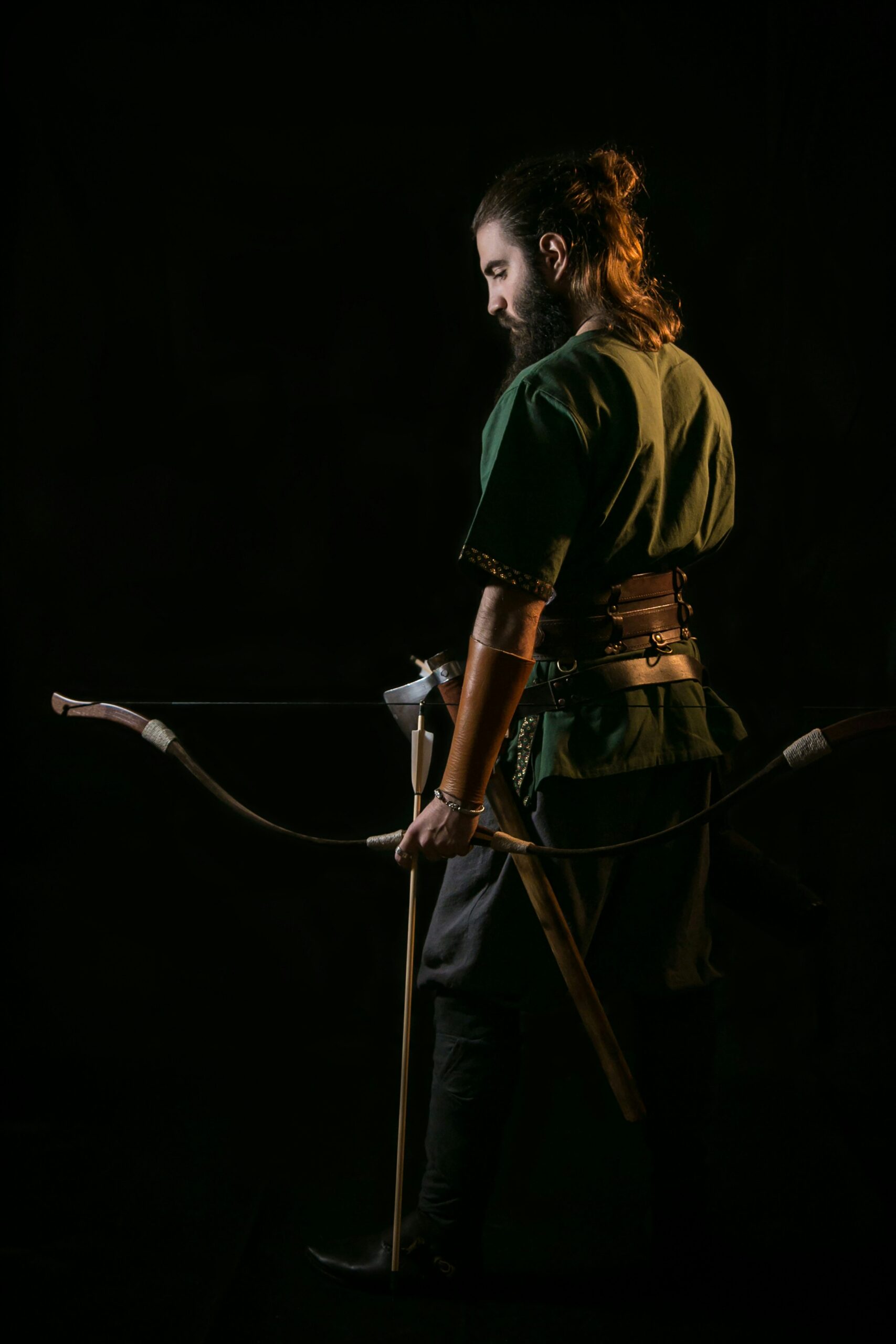 An archer wearing a leather arm guard holds a traditional bow, illustrating protection against bowstring slap during shooting. - Brainy Actz Escape Rooms An archer wearing a leather arm guard holds a traditional bow, illustrating protection against bowstring slap during shooting.