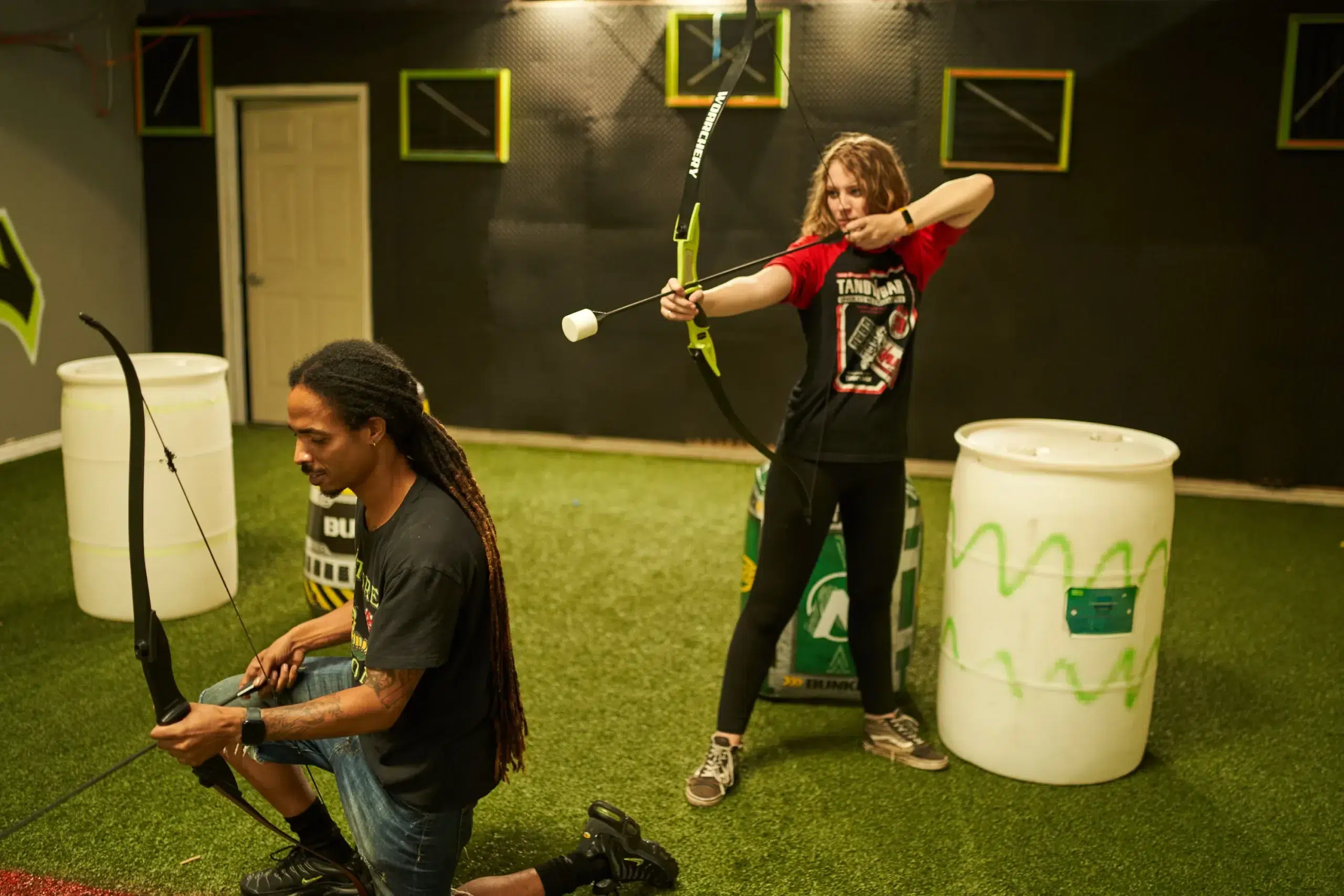Two teammates coordinate during an arrow tag match, highlighting the dynamic roles and strategies used in team-based game variations. - Brainy Actz Escape Rooms Two teammates coordinate during an arrow tag match, highlighting the dynamic roles and strategies used in team-based game variations.