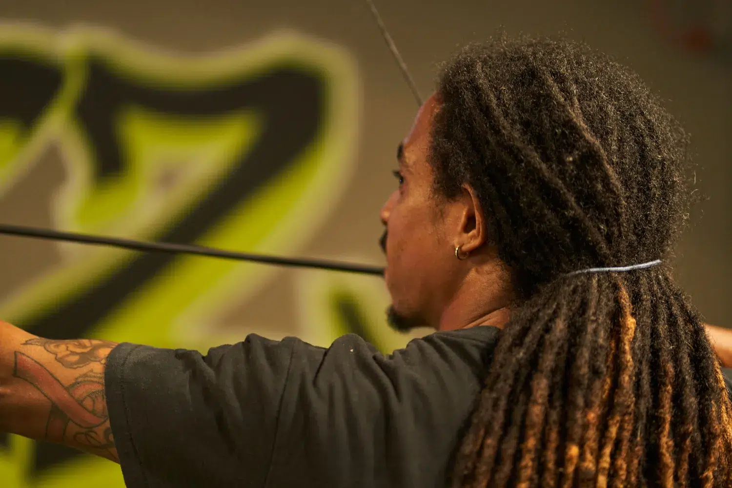 A player draws a bow with focus in an indoor Archery Tag arena, highlighting the importance of strategic target alignment for optimal gameplay positioning. - Brainy Actz Escape Rooms A player draws a bow with focus in an indoor Archery Tag arena, highlighting the importance of strategic target alignment for optimal gameplay positioning.
