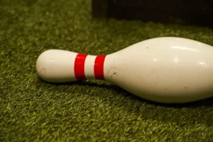 A single fallen Bowlball pin on turf, symbolizing the sport’s blend of football throwing mechanics and bowling fundamentals for beginners. - Brainy Actz Escape Rooms A single fallen Bowlball pin on turf, symbolizing the sport’s blend of football throwing mechanics and bowling fundamentals for beginners.