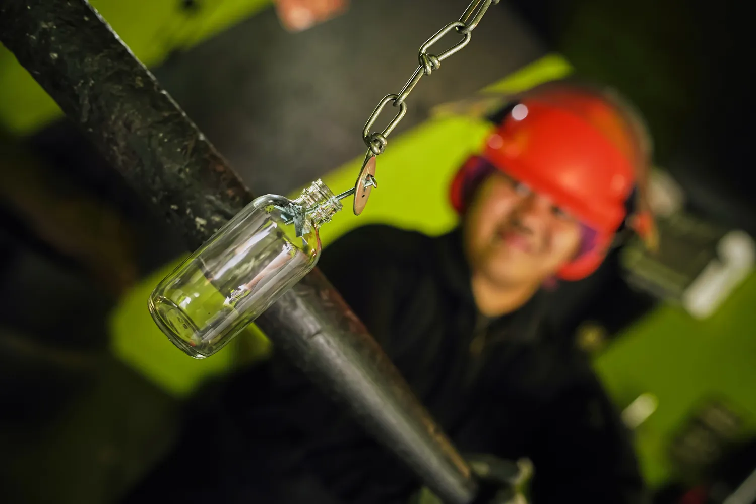 A person in full safety gear prepares to smash a suspended glass bottle with a bat, emphasizing the importance of protective equipment and supervision in rage rooms. - Brainy Actz Escape Rooms A person in full safety gear prepares to smash a suspended glass bottle with a bat, emphasizing the importance of protective equipment and supervision in rage rooms.