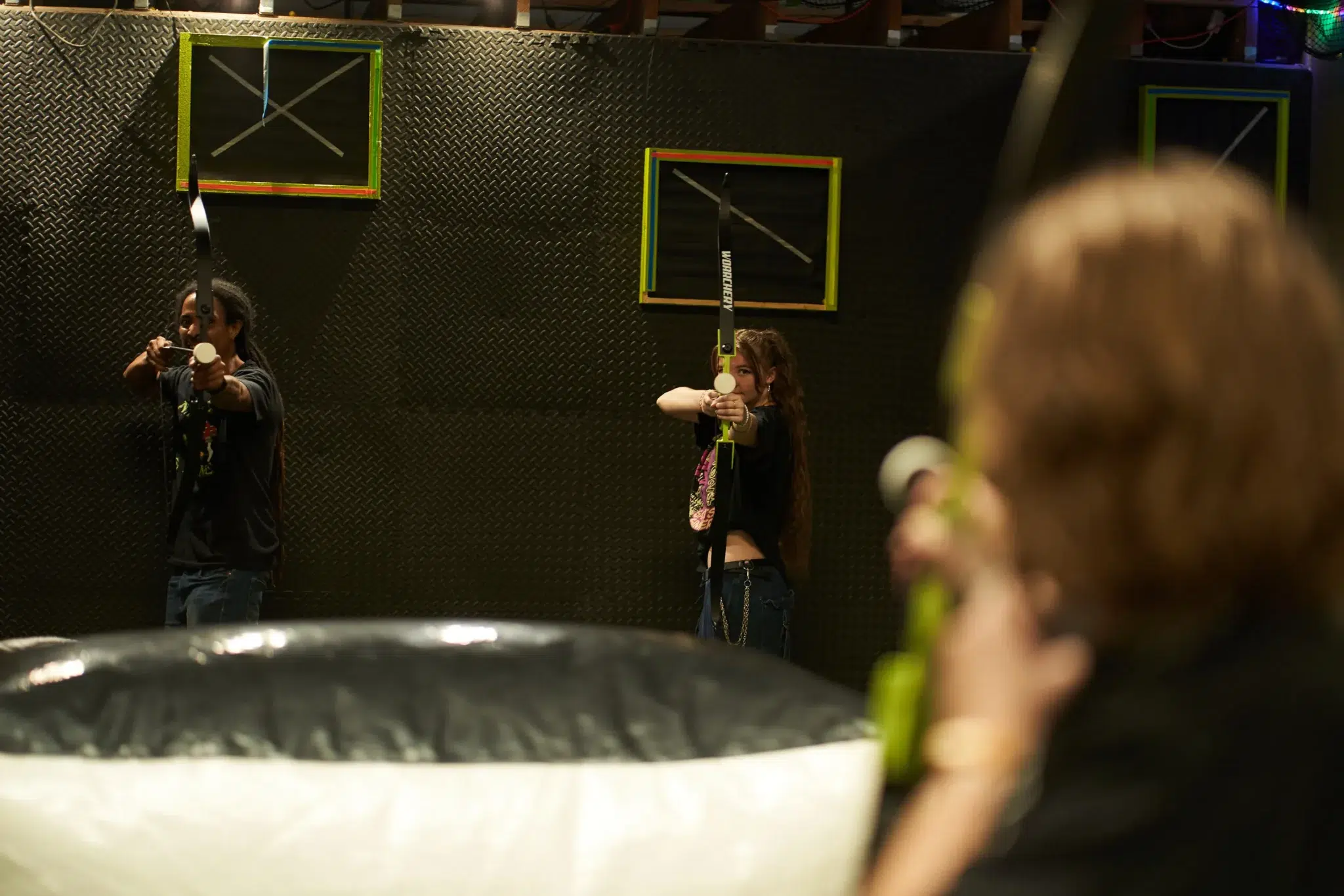 Players aim their foam-tipped arrows in unison during an arrow tag match, showcasing coordination, shared focus, and the essence of collaborative team play.