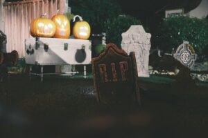 photo 1741755367478 9b377e8a23a2jpeg - Brainy Actz Escape Rooms Halloween graveyard display with jack-o’-lanterns on a coffin and tombstones in Tacoma.